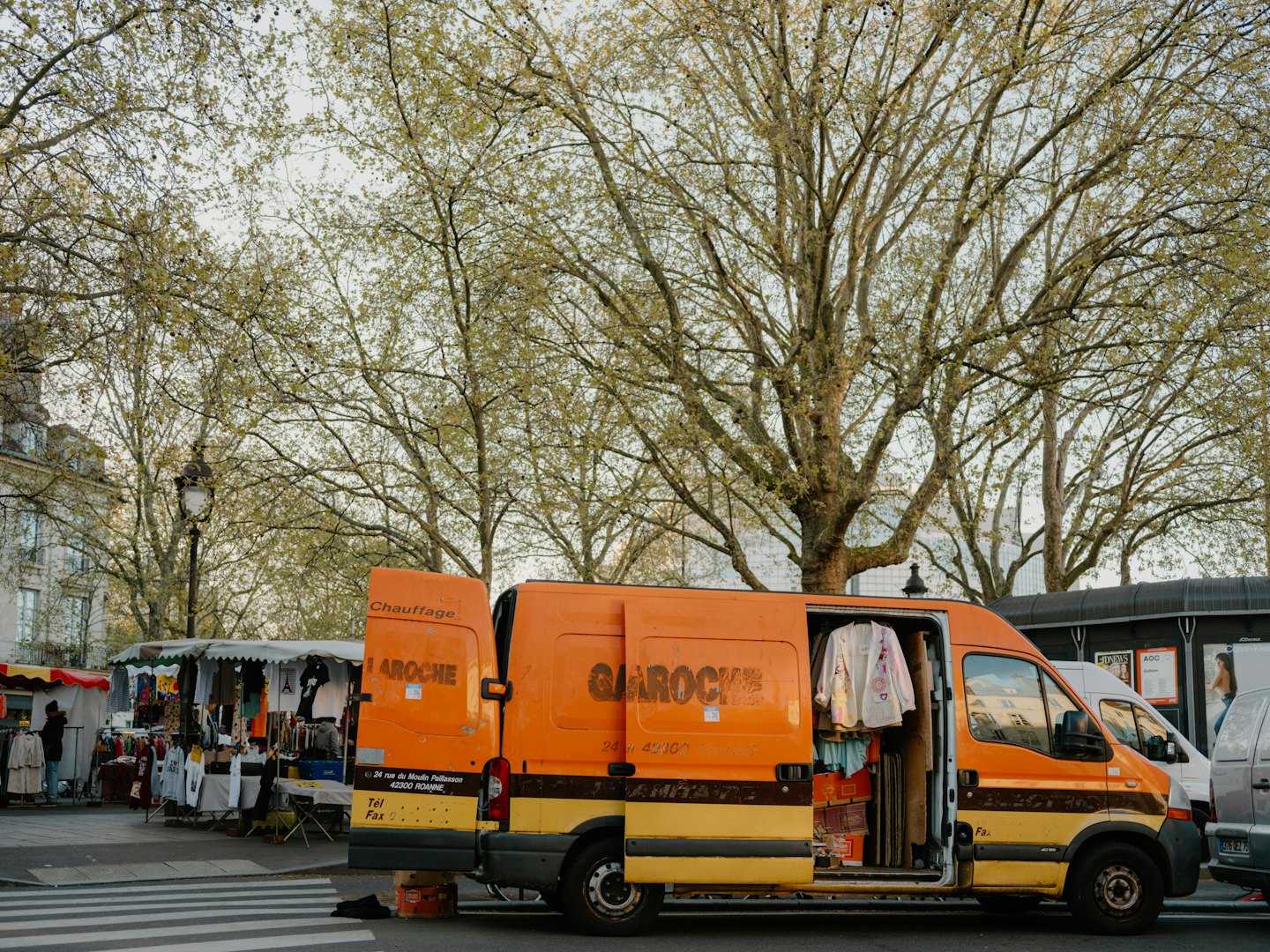 Orange and yellow service van with open doors on a city street.