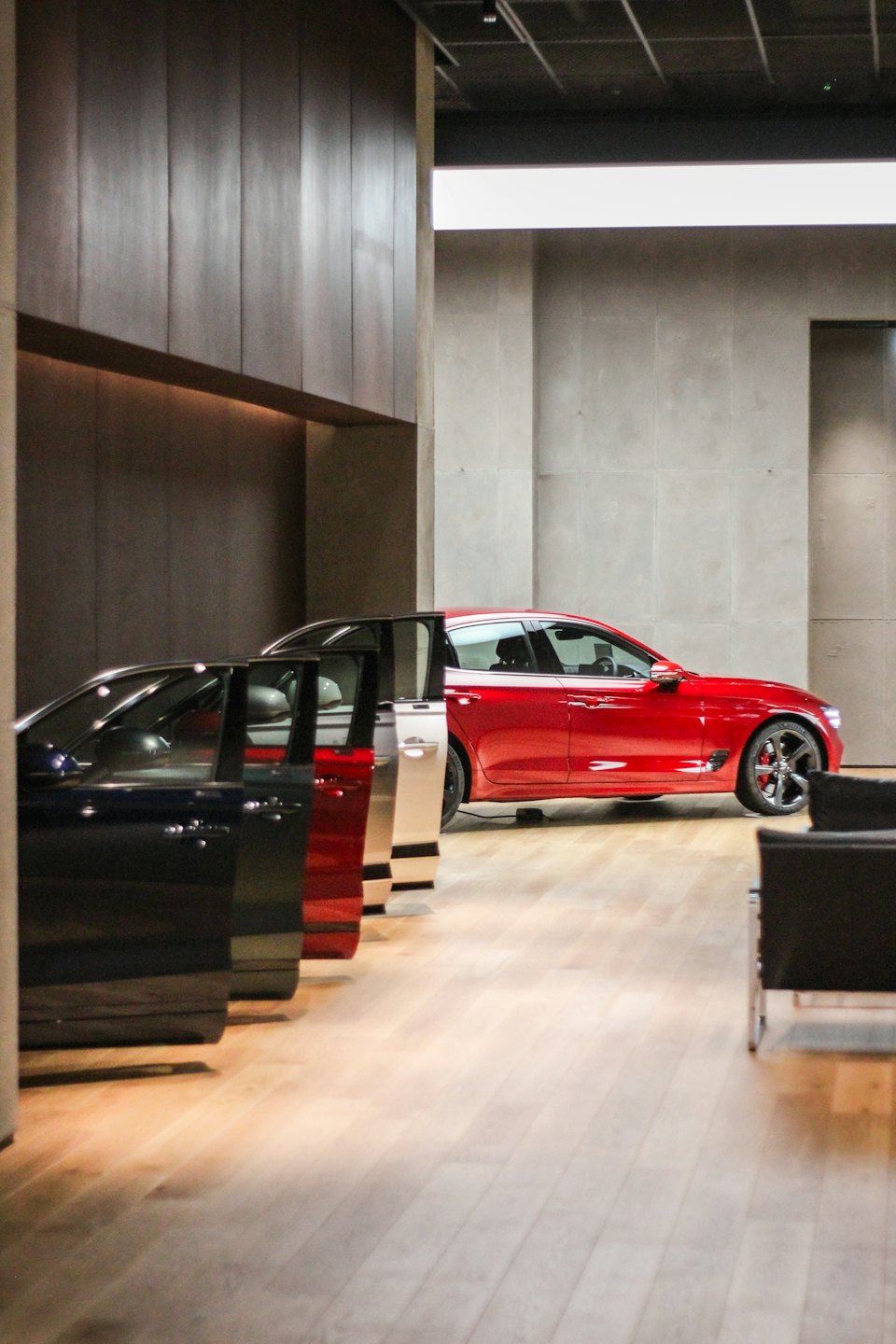 Car showroom displays various car doors and a red luxury sedan.