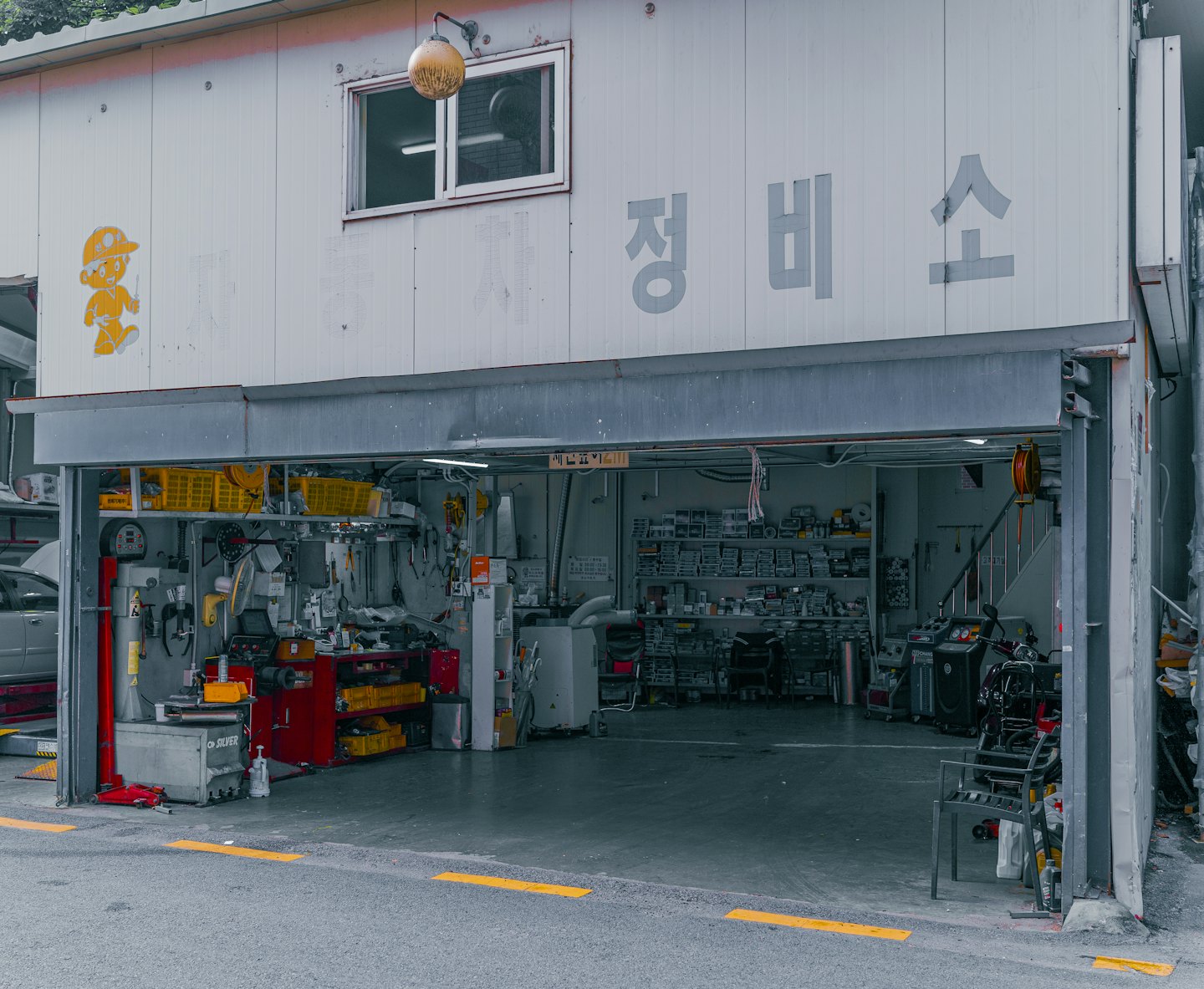 Car repair shop interior visible through an open garage door.