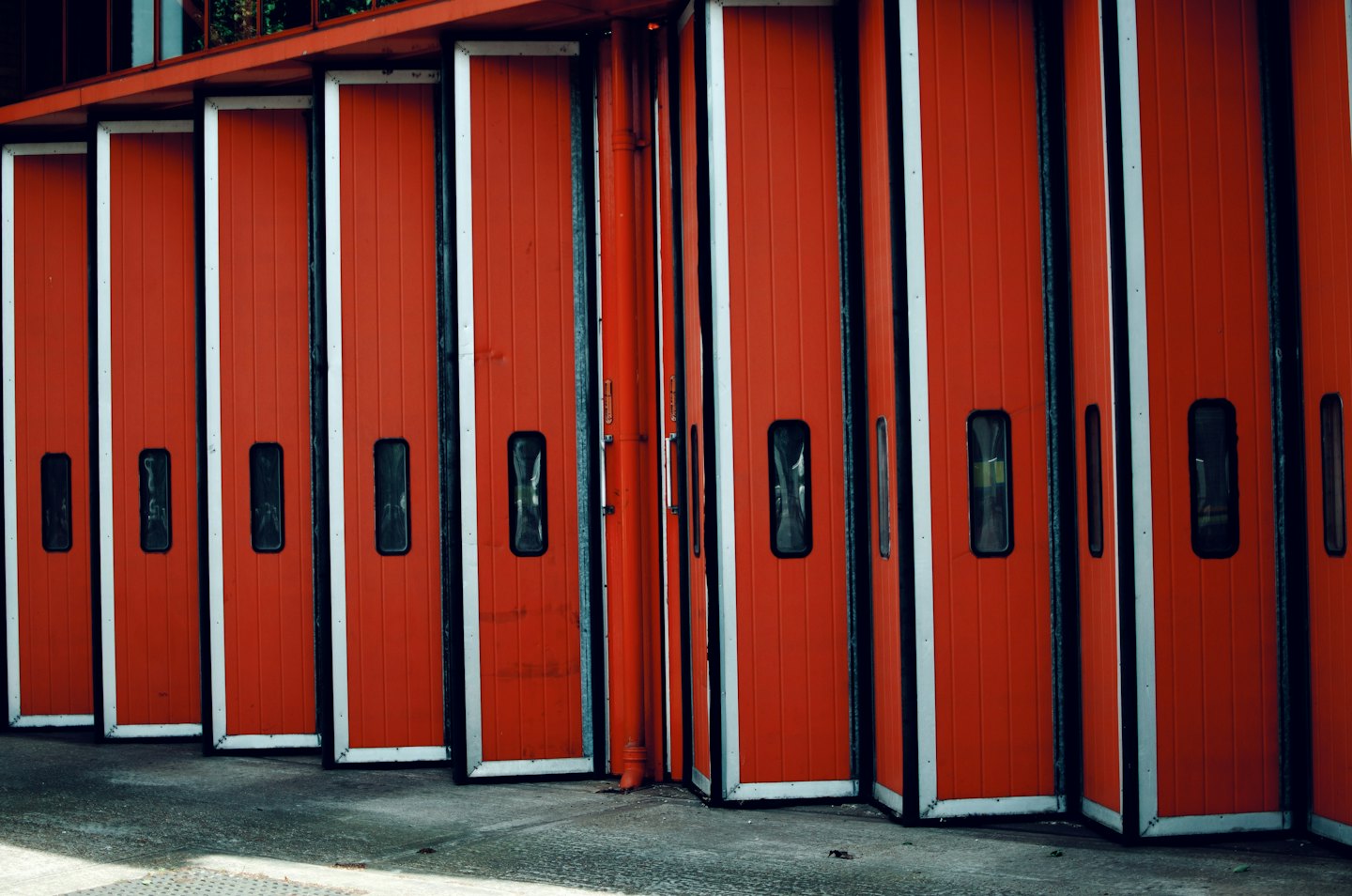 Row of industrial red garage doors with small windows.