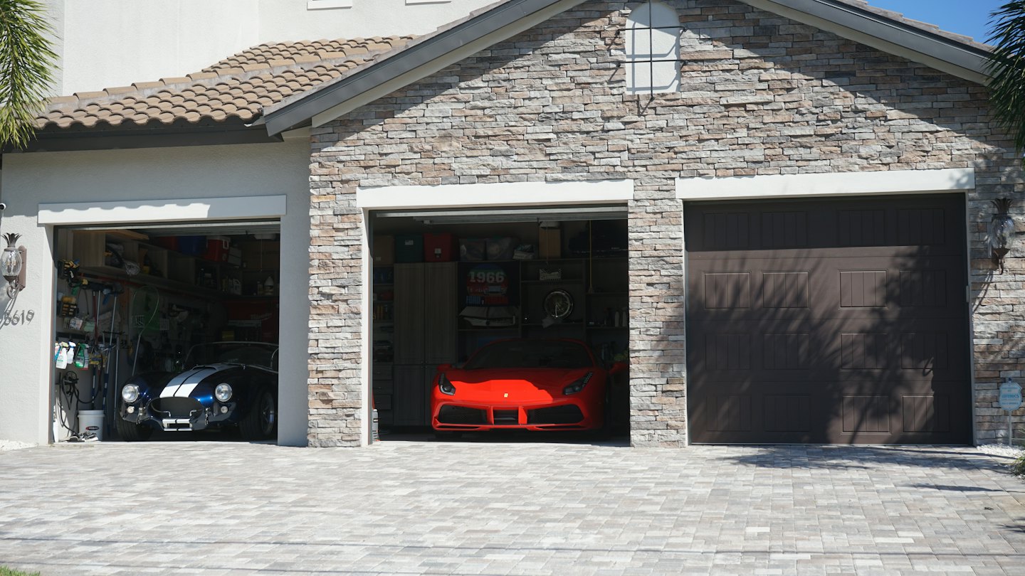 Luxury sports cars parked in a modern multi-car garage.